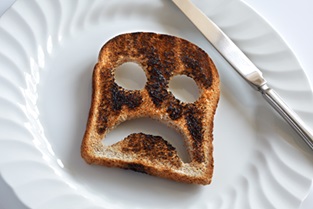 burnt toast with sad face carved out of it placed on a plate
